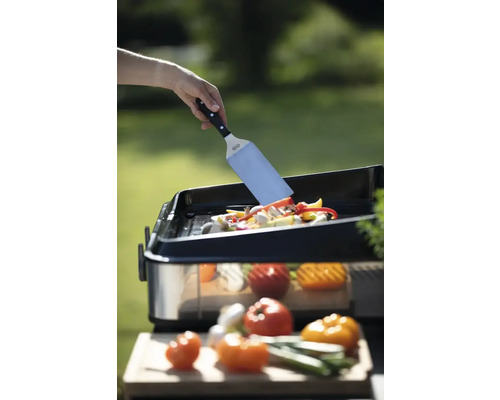 Des légumes sont retournés sur une plaque de gril à l''aide d''une spatule.
