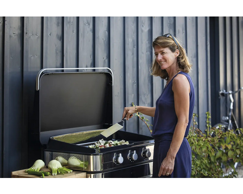 Femme grillant des légumes sur un barbecue à gaz à l''extérieur.