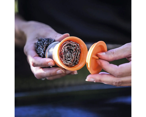 Une personne tient un tampon à récurer en laine d''acier avec récipient et couvercle à la main.