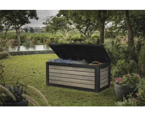 Gartenszene mit einer geöffneten Gartenbox zur Aufbewahrung von Kissen und Decken