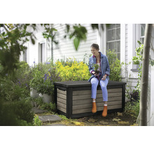 Frau sitzt auf einer wetterfesten Aufbewahrungsbox im Garten