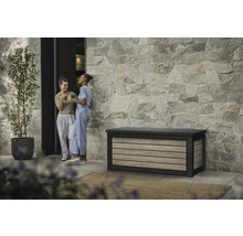 Gartenszene mit Aufbewahrungsbox, Steinfassade und zwei Frauen