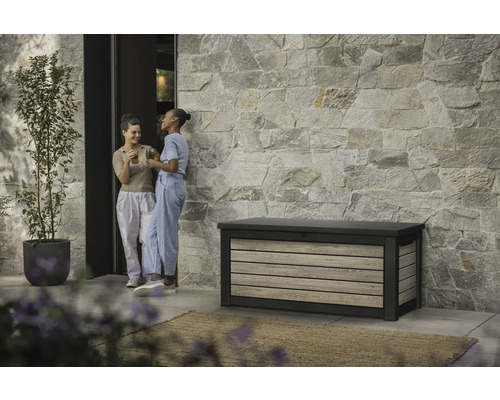 Gartenszene mit Aufbewahrungsbox, Steinfassade und zwei Frauen