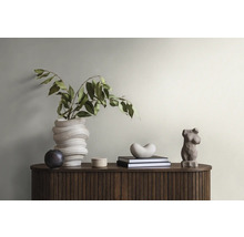 Dekorative Anordnung mit einer Vase, Pflanzen, Büchern und Skulpturen auf einem Schrank