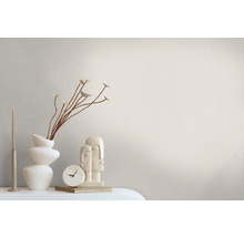 Dekoratives Stillleben mit Kerze, Vase, Blumenzweig, Uhr und Skulptur auf einem Tisch