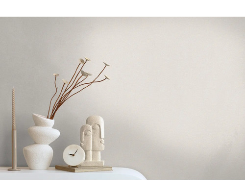 Dekoratives Stillleben mit Kerze, Vase, Blumenzweig, Uhr und Skulptur auf einem Tisch