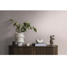 Dekoratives Arrangement auf einem Holzschrank mit einer gewundenen Vase, Blättern, einer weiblichen Torsoskulptur und Büchern