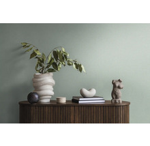 Dekorative Gegenstände auf einem Holzschrank, darunter eine Vase mit Zweigen, Bücher und eine Skulptur