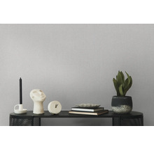 Dekorative Gegenstände wie Kerzenständer, Skulptur, Uhr, Bücher und Zimmerpflanze auf einem schwarzen Regal vor einer strukturierten Wand.