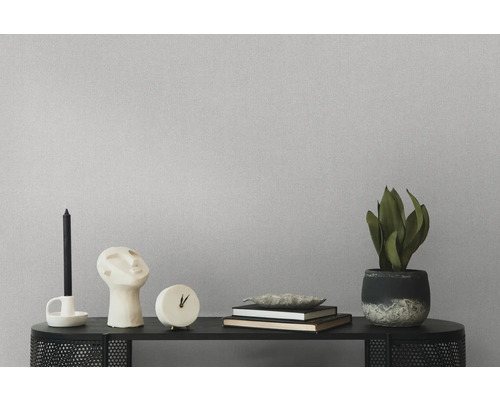 Dekorative Gegenstände wie Kerzenständer, Skulptur, Uhr, Bücher und Zimmerpflanze auf einem schwarzen Regal vor einer strukturierten Wand.