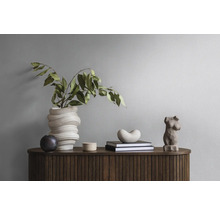 Dekoratives Stillleben mit Vase, Büchern und Skulpturen auf einem Holzschrank