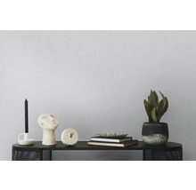 Dekoratives Arrangement mit Kerze, Skulptur, Uhr, Büchern und Topfpflanze auf einem schwarzen Tisch