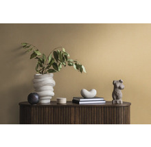 Dekorative Szene auf einem dunklen Holzschrank mit einer weißen Vase, grünen Blättern, Büchern und Statuen.