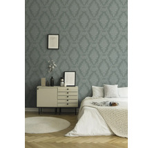 Schlafzimmer mit gemusterter Tapete, Kommode, Bett und rundem Teppich