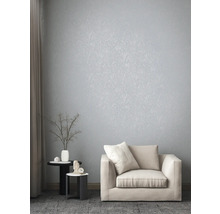 Helles Wohnzimmer mit floral gemusterter Tapete, Sessel und Beistelltischen.