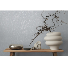 Dekoratives Interieur mit floral gemusterter Tapete und verschiedenen Objekten auf einem Holzregal