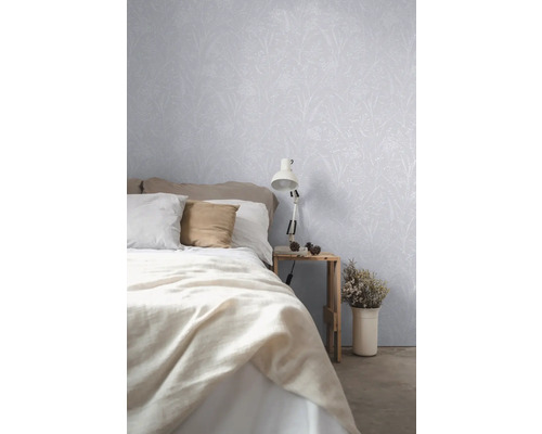 Schlafzimmer mit Bett, Nachttisch, Lampe und Tapete mit Pflanzenmuster