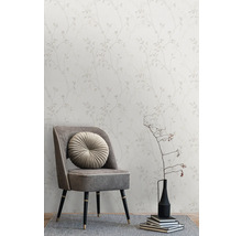 Tapete mit Blätterdesign hinter einem Sessel mit rundem Kissen