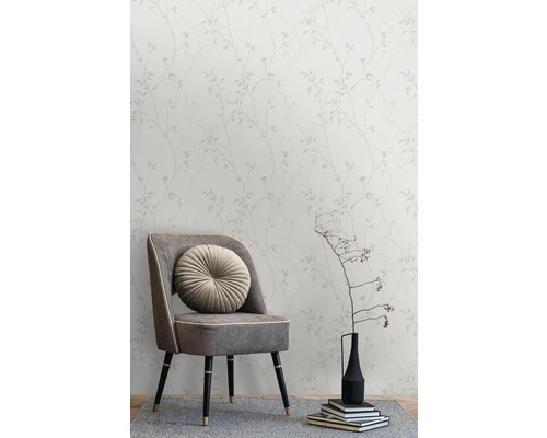 Tapete mit Blätterdesign hinter einem Sessel mit rundem Kissen