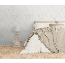 Schlafzimmer mit floraler Tapete, Bett und Lampe auf einem Bücherstapel