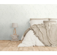 Helles Schlafzimmer mit floraler Tapete, Bett und Nachttischlampe