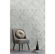 Tapete mit Blätterdesign im Interieur mit Stuhl, Kissen und Dekoration