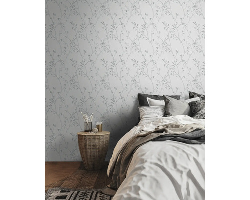 Schlafzimmer mit Wandtapete mit Pflanzenmuster und Doppelbett.