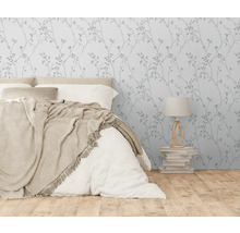 Schlafzimmer mit Bett, Nachttischlampe und Tapete mit Pflanzenmuster