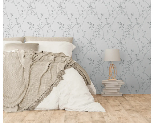 Schlafzimmer mit Bett, Nachttischlampe und Tapete mit Pflanzenmuster