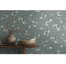 Dekorative Wand mit Eukalyptusmuster und Wohnaccessoires auf einem Tisch.