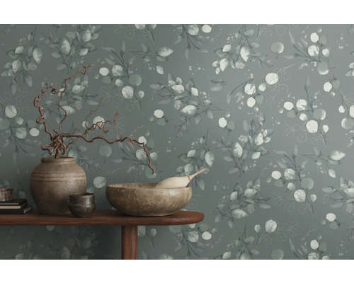 Dekorative Wand mit Eukalyptusmuster und Wohnaccessoires auf einem Tisch.