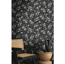 Raumansicht mit einer Tapete mit Eukalyptuspflanzenmuster hinter einem Holzstuhl und Beistelltisch.