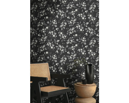 Raumansicht mit einer Tapete mit Eukalyptuspflanzenmuster hinter einem Holzstuhl und Beistelltisch.