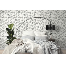 Schlafzimmer mit floral gemusterter Tapete, Bett und Stehlampe