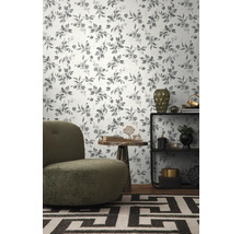 Dekoriertes Wohnzimmer mit einer Tapete mit Eukalyptuspflanzenmuster, einem Sessel, einem Tisch und einem Regal.