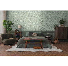 Schlafzimmer mit Bett, Sessel, Kommode und floraler Tapete.