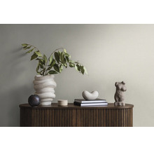 Dekoratives Sideboard mit Büchern, Statuen und Vase mit Grünpflanze.