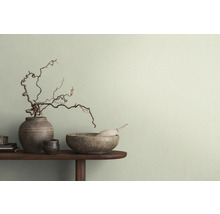 Dekorative Szene mit Vasen, Schalen und Ästen auf einem Tisch vor einer Wand