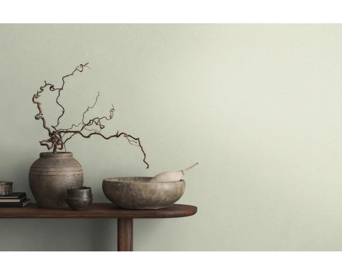 Dekorative Szene mit Vasen, Schalen und Ästen auf einem Tisch vor einer Wand