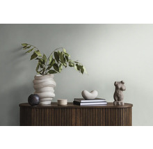 Dekoratives Arrangement mit Vase, Skulpturen und Büchern auf einem Holzschrank.