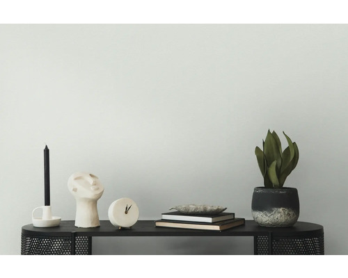 Dekorative Szene mit Kerze, Skulptur, Uhr, Büchern und Topfpflanze auf einem schwarzen Tisch