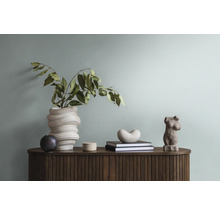 Dekoratives Arrangement auf einem Holzschrank mit Vase, Pflanze, Büchern und Skulpturen.