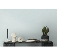 Dekoratives Arrangement mit Kerze, Skulptur, Uhr, Büchern, Schale und Pflanze auf einem Tisch