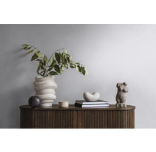 Dekoratives Arrangement auf einem Holzschrank mit Vase, Pflanzen, Büchern und Skulpturen.