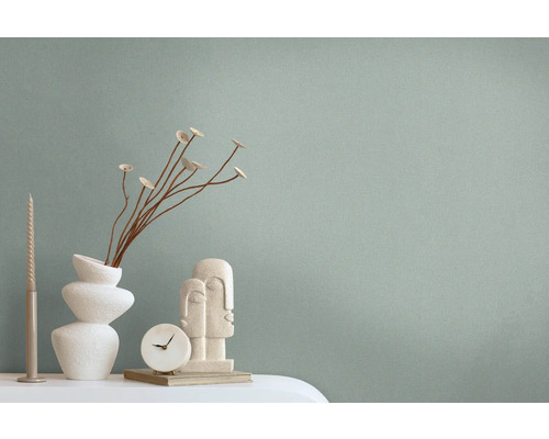 Dekorative Szene mit einer Vase, Zierblumen, einer Skulptur, einer Uhr und einer Kerze auf einem Tisch