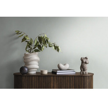 Dekoratives Arrangement auf einer Kommode mit Blumenvase, Büchern und Skulpturen.