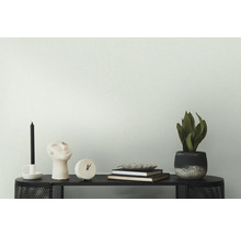 Dekoratives Arrangement auf einem schwarzen Tisch mit Kerze, Skulptur, Uhr, Büchern und Zimmerpflanze