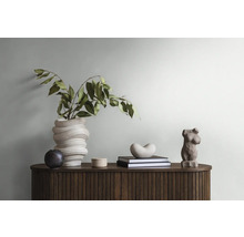 Dekoratives Interieur mit Holzkommode, Vase mit Grünpflanze, Büchern und Skulpturen.