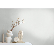 Dekorative Szene mit Vase, Zierblumen, Kerze, Tischuhr und Skulptur auf einem Tisch