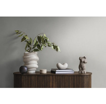 Dekoratives Stillleben mit Blumenvase, Büchern und Skulpturen auf einem Holzschrank